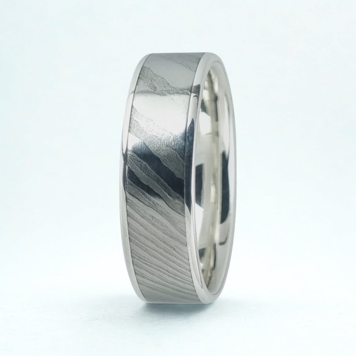 Silver ring with a damascus pattern on a white background