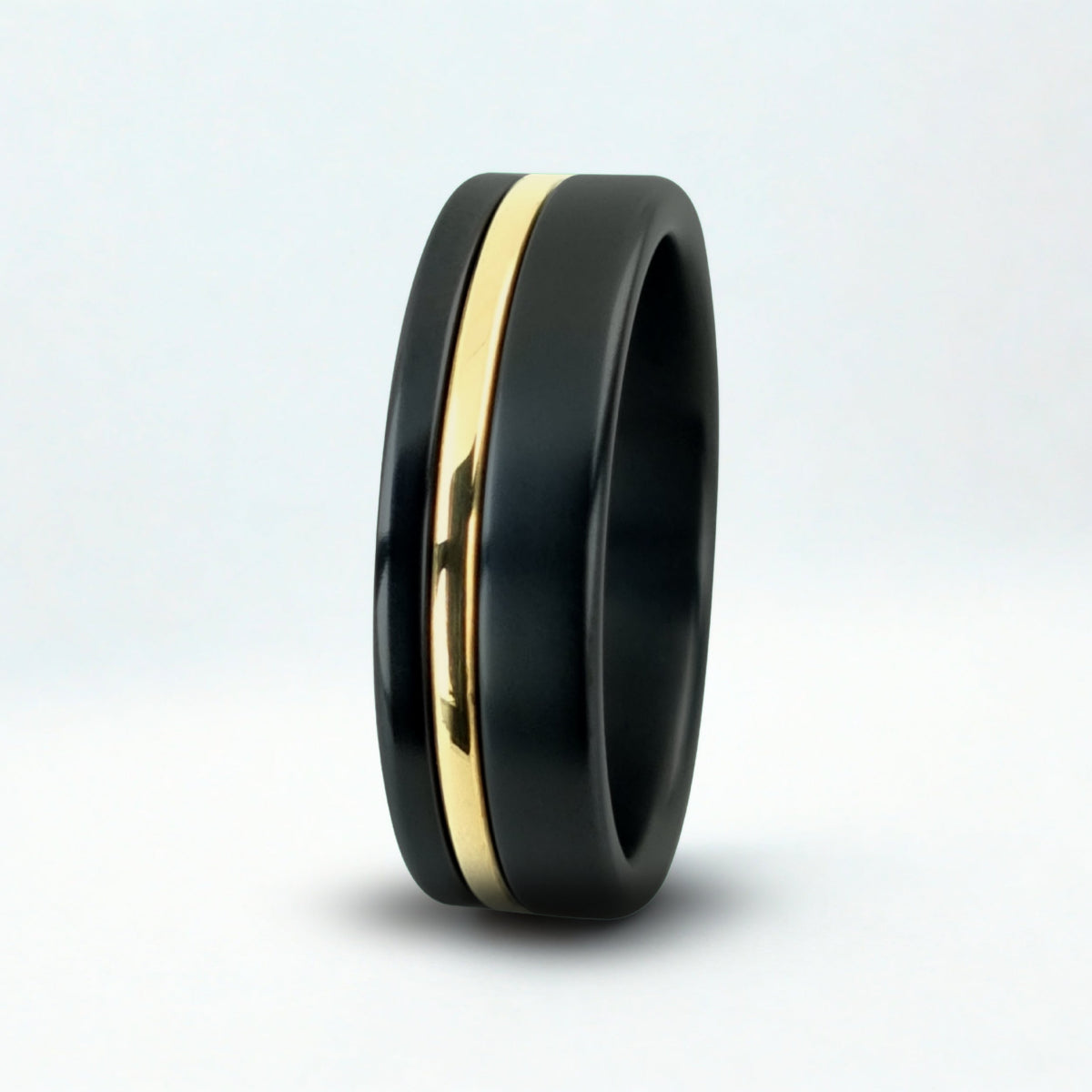 Black ring with a gold inlay on a white background