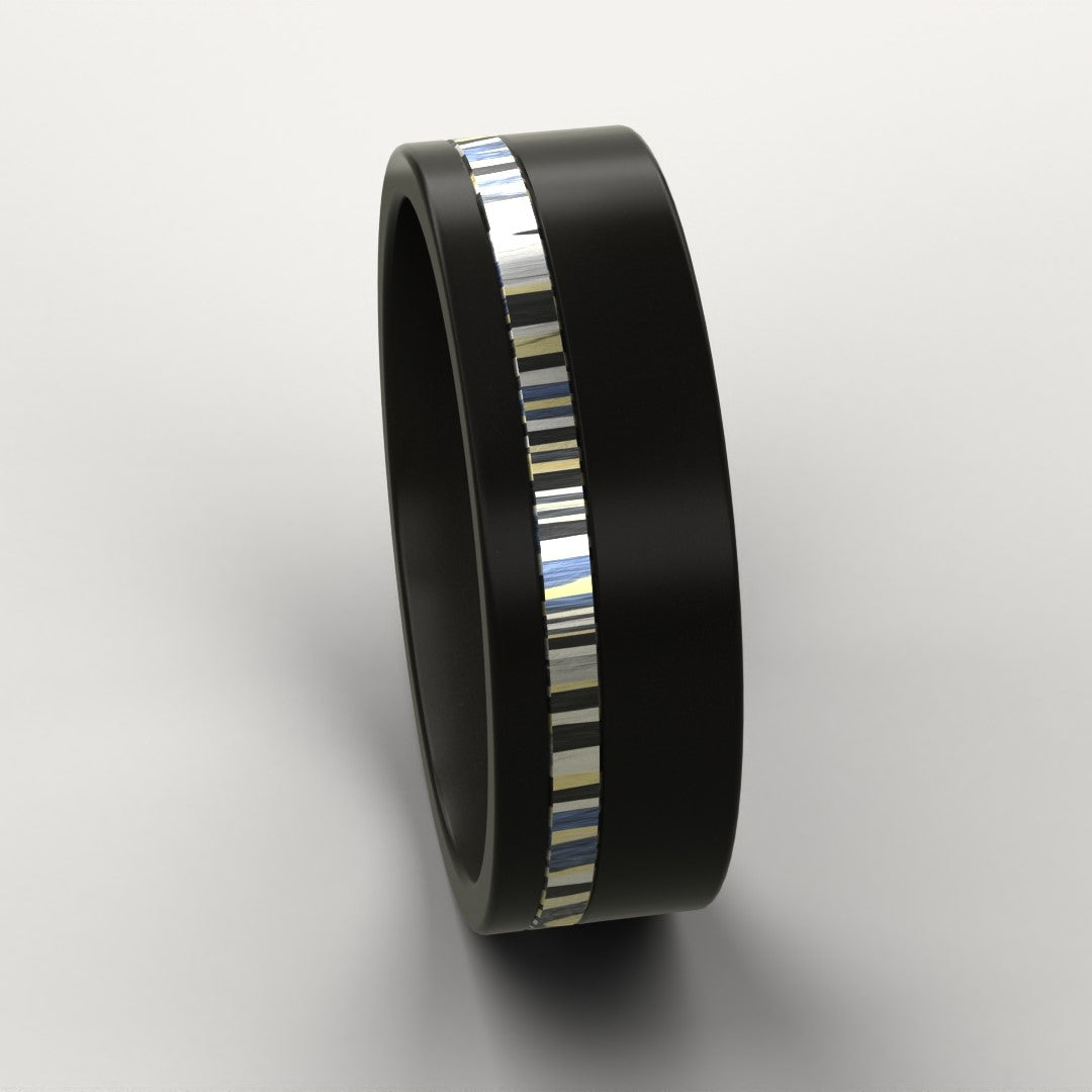 Black ring with a colourful patterned metal inlay on a light grey background