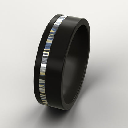 Black ring with a colourful patterned metal inlay on a light grey background