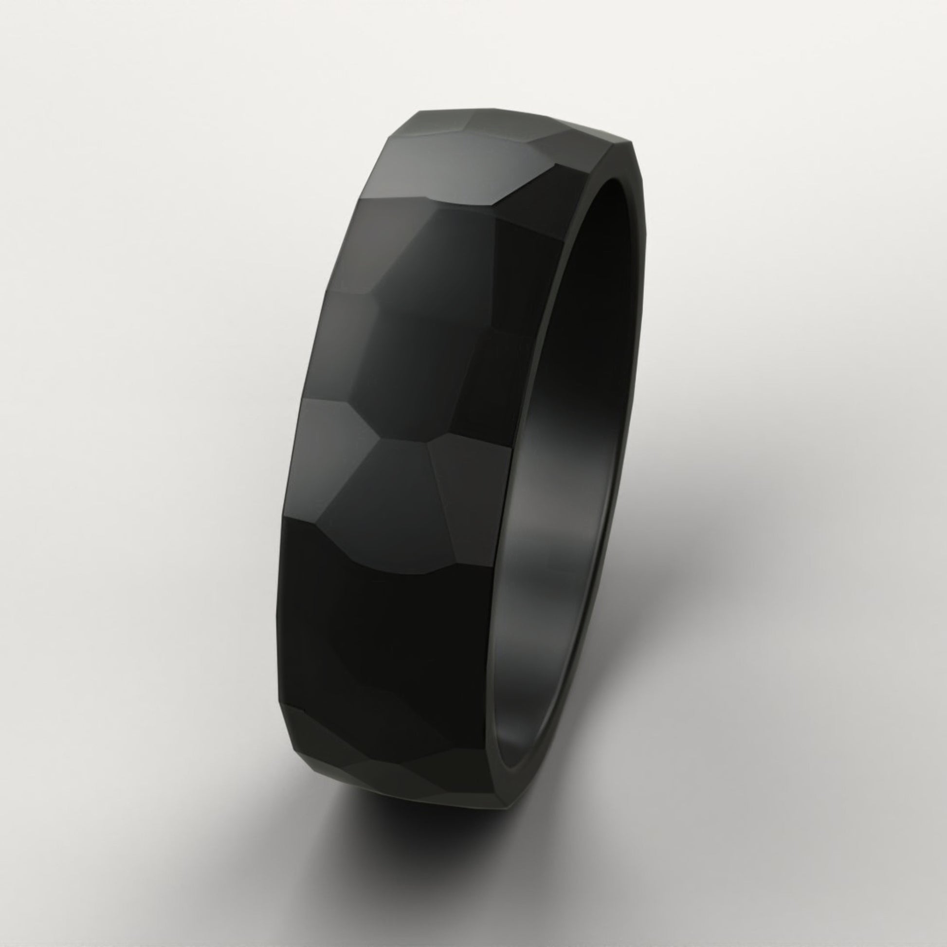Black faceted ring on a light gray background